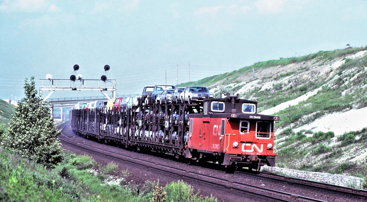 Just over 40 years ago, the west end of an eastbound freight is shown with brakes applied as the unknown train slows for the diamond at Doncaster on CN's York Subdivision. Interesting features in this photo include brake shoe smoke, open bi and tri-level auto racks, and of course the caboose. Also of interest is the railways' ability back then to load trucks on the top deck of tri-levels.