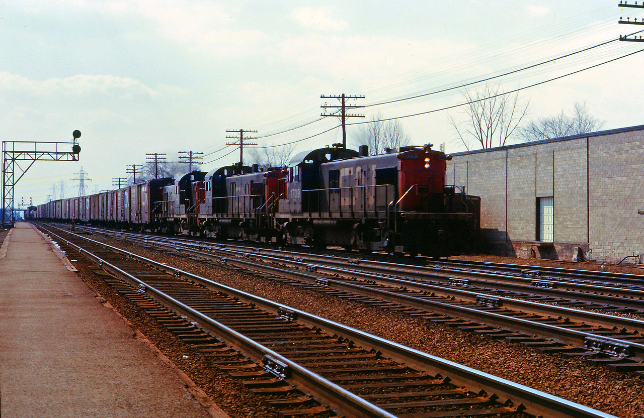 CN didn't buy any RS1s but it did have a similar MLW-designed units, the 1000 hp A1A-truck RSC13. These units replaced steam on many branch lines in Ontario and Quebec (and initially on Vancouver Island!). Around 1965, 13 of these engines had the centre axle removed and were assigned to tranfer duty in the Toronto and Montreal areas. (The middle axle was later re-installed and the units assigned to the Maritimes until their retirement in the mid-1970s.) Here we see three  "tractors" leading an eastbound train onto the Halton sub at Burlington.

(If RSC13s were "tractors" and SW1200RS' were "pups"...I wonder what the nickname was for GMD1s?)