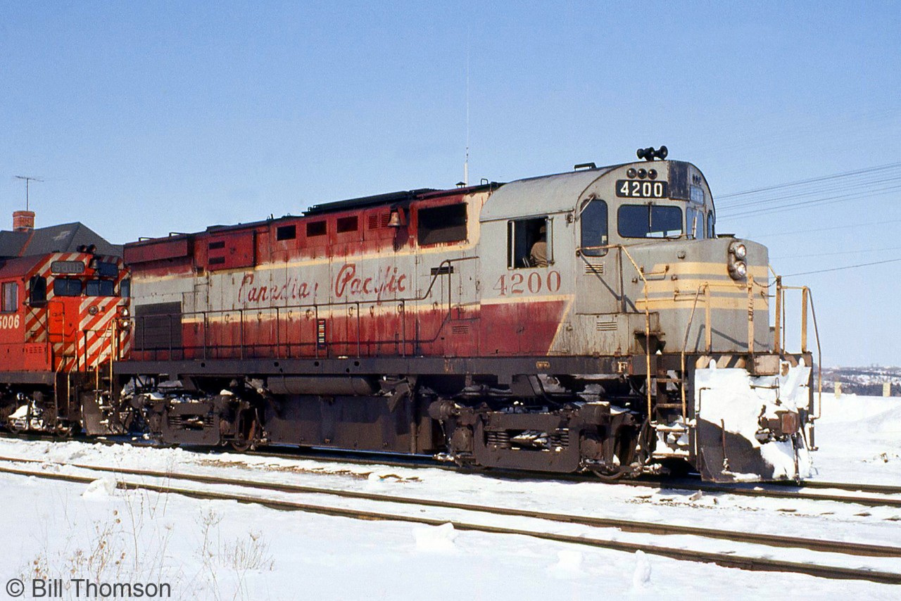 Canadian Pacific C424 4200 (the former CP 8300) is pictured still sporting her faded maroon & grey script livery, with CP GP35 5006 on the head end of a freight at Bolton on March 25th 1972.

As an initial one-unit sample order, CP's first C424 (and the first C424 ever built by MLW or Alco) had a few differences from other CP units, including the fuel tank, dynamic brake hatch, rear radiator style, hood details, battery boxes around the cab, deck-mounted stanchions, and a higher-mounted headlight that was originally on the flat plate of the cab (4201-4209 were also delivered with high-mount headlights, but units 4210 and over had it on the nose). In the mid-late 60's, the early units with high headlights all had them relocated to the nose, as seen here.