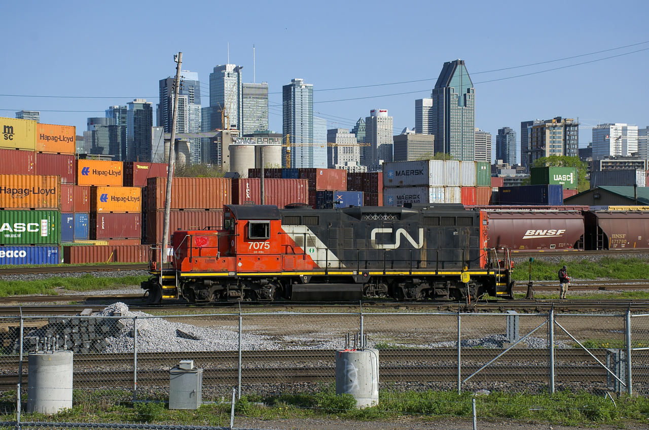 CN 7075 idles in the Pointe St-Charles Yard just before coupling to CN 7229. In the background is the skyline of downtown Montreal.