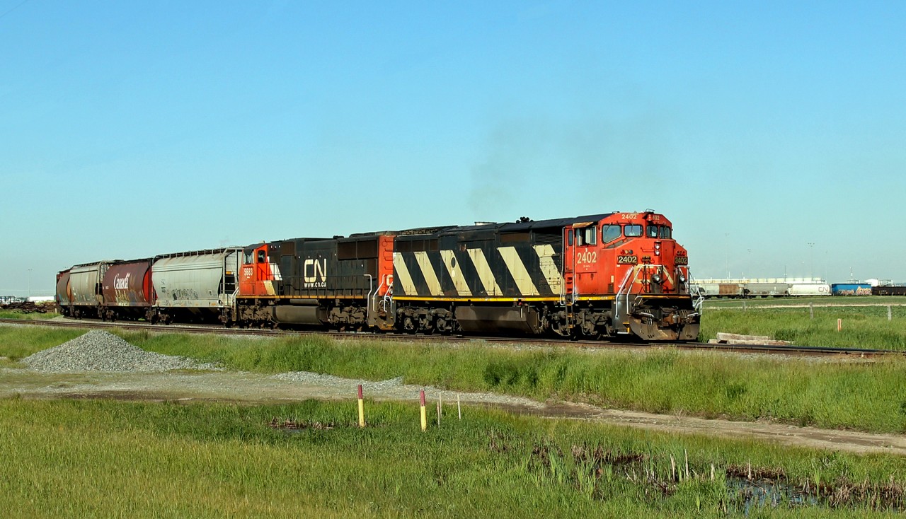 DASH 8-40Cm CN 2402 and SD75I CN 5683 ease around the curve as they approach Scotford Yard
