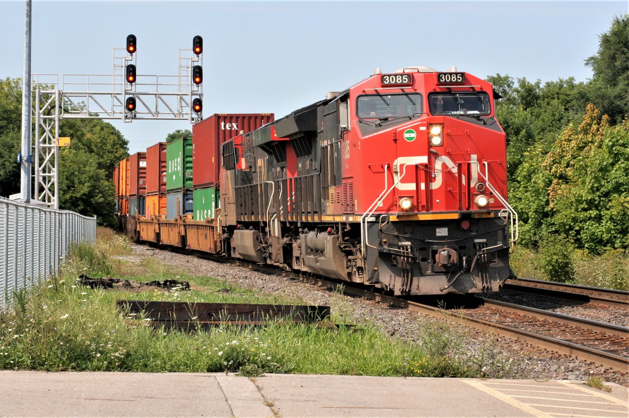 CN 3085 leads a lengthy 148 through Georgetown just before noon on a cloudless summer morning.