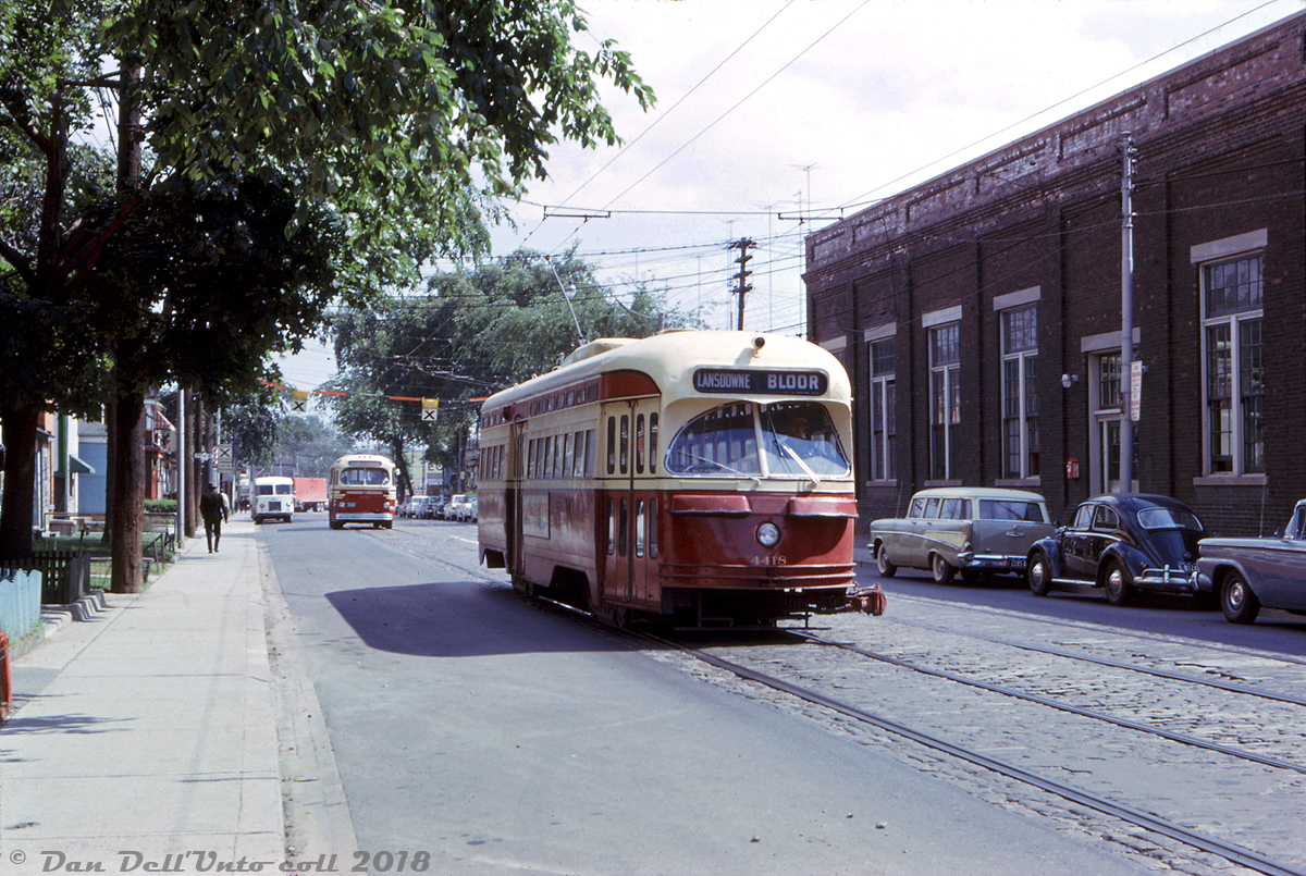 TTC PCC 4418 (an A7-class car built in 1949, note front coupler for MU operation on busy routes) is deadheading northbound out of service on Lansdowne Avenue near Paton Road, about to turn into the Lansdowne Carhouse (on the right) after running in evening rush-hour service on Bloor Street. Following behind is what appears to be a 9000-series Can-Car trolleybus, possibly also deadheading or operating on an in-service Route 47 Lansdowne run. One would note that Toronto had its fair share of Volkswagen Beetles back in the day, as evident by the black one parked curbside. 

Both streetcars and trolleybuses were based out of Lansdowne Carhouse until the Bloor-Danforth subway opened in 1966, after which point it mainly became home to diesel buses and trolleybuses like the Can-Cars, later Flyer E700's, and leased Edmonton BBC/GM's until the carhouse/garage was closed in the mid-1990's. Even though it was eventually demolished, soil contamination issues (it was originally constructed by the Toronto Railway Company way back in 1910) prevented any redevelopment until recently.

Robert D. McMann photo, Dan Dell'Unto collection slide