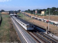 Morning light shines on this scene at Eglinton Avenue West, as a six-car train of Hawker Siddeley subway cars departs Eglinton West Subway Station northbound on the new Spadina line, bound for Wilson station to the north. The first and last two cars appear to be earlier HSC models (the lead two are <a href=http://www.railpictures.ca/?attachment_id=37314><b>H1's</b></a>), with the middle two cars being newer <a href=http://www.railpictures.ca/?attachment_id=12120><b>H5's</b></a> ordered specifically for the <a href=http://www.railpictures.ca/?attachment_id=36309><b>new Spadina line</b></a> extension. <br><br> Nearby, a colourful assortment of morning automobile traffic clogs the southbound off-ramp of the Allen Road waiting to turn onto Eglinton Avenue. Since the original Spadina Expressway plan got nixed by local and political opposition (which saved the neighbourhoods to the south that were to be bulldozed for it, plus the ravine lands and downtown Spadina Avenue), the completed expressway stub known as the Allen Road was dead-ended at Eglinton Avenue and dumped all its southbound traffic onto Eglinton. Backed-up traffic conditions are still a problem on this stretch today, with no real resolution possible: bulldozing well-established neighbourhoods for expressways went out of style with the 70's, the political fallout from doing such actions today would be massive, and all the high-priced Toronto real estate would make that kind of land expropriation a very costly affair. <br><br> <i>Edward (Ted) Wickson photo, Dan Dell'Unto collection.</i>