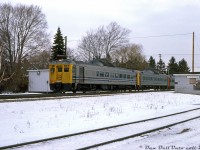 A train of VIA Rail Budd RDC's (in three different liveries: VIA-CN, VIA, and CN) head westbound through snowy Clarkson, passing the old CN Clarkson Station, long out of use and falling into disrepair. There would be no station stop here for the Budds today, nor has there been for nearly a decade. <br><br> This small iteration of Clarkson Station was built by CN as a replacement for the <a href=http://www.railpictures.ca/?attachment_id=13305><b>previous GTR-built Clarkson Station</b></a> that had burned down in 1962. But the new station would see only a few years of use, as regular passenger service here ended on Saturday May 20th 1967, the last day of CN's commuter train operations between Hamilton and Toronto (Mon-Sat CN trains #921 & #922 would be the final two to use the station, according to a 1965 timetable). Three days later, government startup commuter service operator GO Transit would start running trains on their Lakeshore corridor using the new Clarkson GO Station built to the west. As far as I have been able to find, CN's Clarkson Station building here met its eventual demise sometime between 1978 and 1984. <br><br> According to Wilfred Sergeant's "Building GO Transit" (2004) e-book, there were a number of decisions influencing this move. The CN station here was located in what once was the old "Clarkson's Corners" village and was constrained by established development and small local roads. However, land to the west along Southdown Road was vacant and presented the opportunity for better traffic flow via a grade separation, better traffic access off the main roads, and ample land for parking lots. CN's stations at Long Branch, Dixie Road, Lakeview and Lorne Park* would also suffer similar fates, either closed down and replaced with new GO stations in better locations, or consolidated with others nearby in order to achieve optimal station spacing for better train timing. <br><br> <i>*Note, due to strong local community opposition, CN's Lorne Park station remained and had *one* GO train run scheduled to serve there each morning (GO #954 from Hamilton to Toronto, that would stop at Lorne Park instead of Clarkson at 7:58am each morning), until it was rescheduled to Clarkson after about a year.</i> <br><br> <i>Douglas J. Fear photo, Dan Dell'Unto collection.</i>