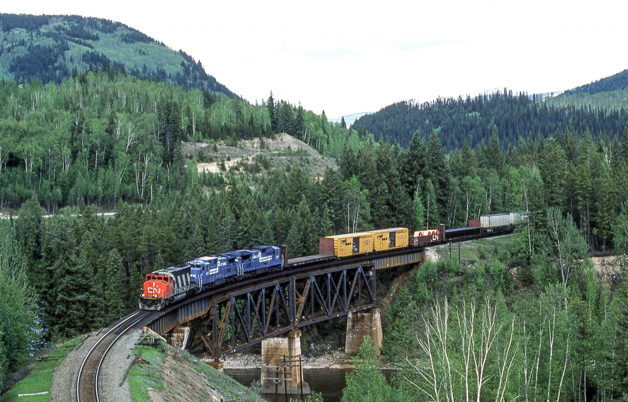 It was a cloudy May 19, 1986 west of Avola, British Columbia when Peter Jobe photographed CN 5289 and CR 6618 and CR 6619 crossing the North Thompson River. This was CN train #201.