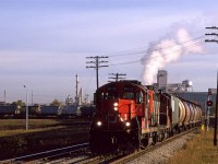 Train 520, the Camrose turn, has just left the Wainwright Sub, and is now headed south on the Carmose Sub. In tow, it a lengthy string of grain hoppers,
The steam is coming from a Celenese chemical plant,that has since disappeared.