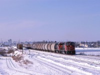 This empty potash train likely started off at Bissell Yard, on the west side of town a few minutes ago, bu-passing Walker Yard on its south side. They will likely exchange power, or simply pick another locomotive before the return trip.
This area was once filled with stock yards. Only Swict surved at this time and they received their animals via truck. The track sloped down at left leads to their facility. Although it is plowed, I do not ever recall seeing rail cars on that spur.
Tracks visible on the roght are the wye for the Vegreville Sub