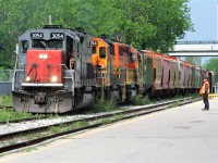 A Goderich-Exeter Railway (GEXR) employee watches as train 431 slowly trundles down the siding by the VIA Rail station in Kitchener on a warm spring afternoon. Powering the train is big GEXR SD45T-2 3054, GEXR SD40-2 3394 and RLHH SD40-2 3403. 
