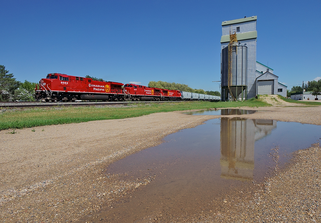 CP 321 rolls through Austin, Manitoba with a trio of washed GE's leading a long string of new grain hoppers.