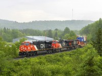 During a downpour, stack train Q121 rounds the bend at Lac Baker, New Brunswick. 