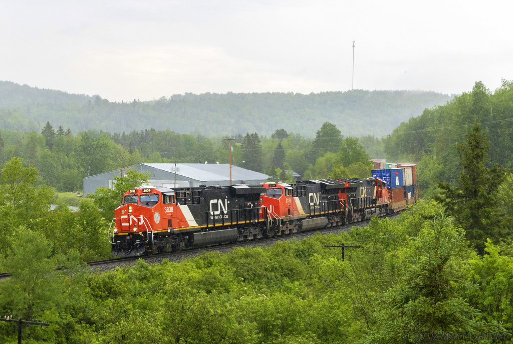 During a downpour, stack train Q121 rounds the bend at Lac Baker, New Brunswick.