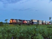 During blue hour, stack train Q120 rounds the bend at Upper Dorchester, New Brunswick. 
