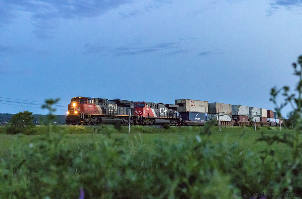 During blue hour, stack train Q120 rounds the bend at Upper Dorchester, New Brunswick.
