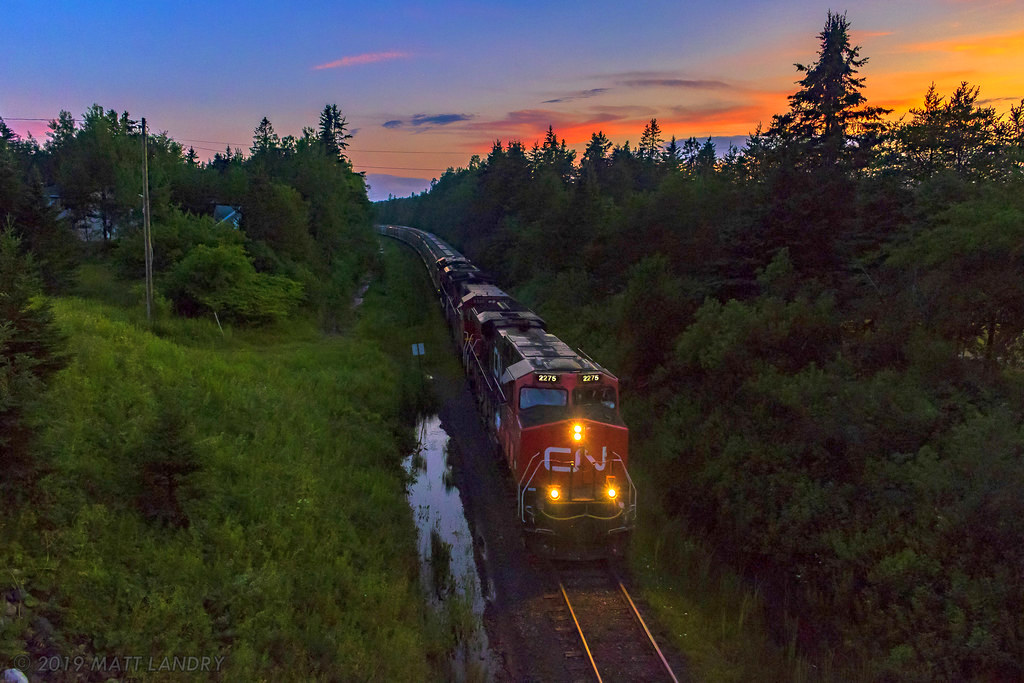 In day's last light, train 406 descends down the grade at Quispamsis, about 8 miles east of Saint John, New Brunswick. It was about a three mile uphill climb, cresting about a mile from my location. With a train of mostly empties, it wasn't a huge challenge.