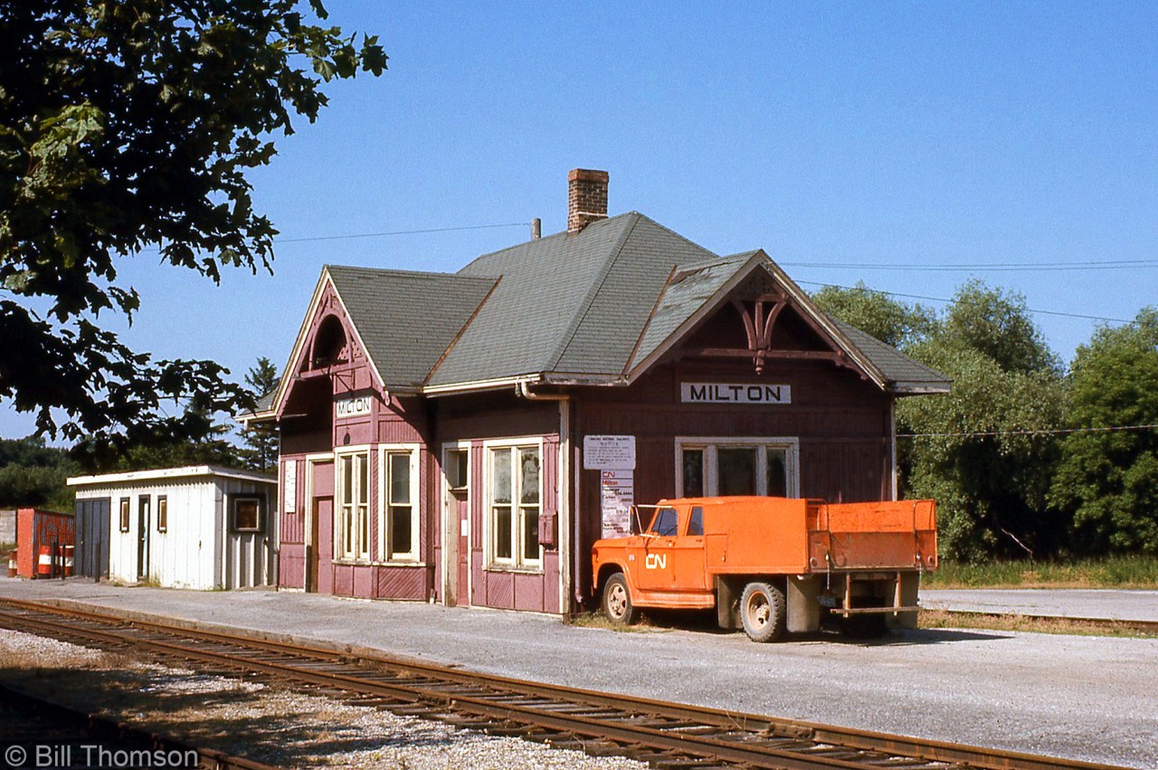 CN's Milton Station is pictured in 1973 at its original location, along the former mainline that at the time of this photo was now a short spur.

The CN line through Milton was originally built as the Hamilton & Northwestern Railway, eventually becoming CN's Milton Subdivision. The line, which crossed CP's Galt Sub at an interlocking diamond north of the station, was grade-separated and realigned to the west through town around 1963-64, becoming part of CN's new Halton Subdivision.

The old alignment became a short spur line, the Milton Townline Spur, that ran south to the old station area here to serve the Robertson Screw factory nearby. The CN-CP diamond was removed circa 1973-74, and CP then served Robertson Screw into the 80's via a connecting track of their Galt Sub to part of the former CN trackage. CN's Milton Station was moved to north end of town, and serves as a tourist information building in Chris Hadfield Park.