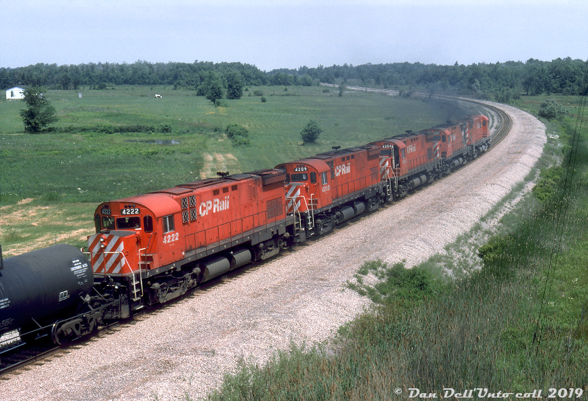 After climbing the grade out of the Welland Canal tunnel, a solid set of five MLW C424's are working hard as they smoke it up at the head end of a CP acid train, rolling around the curve at Netherby Road (Highway 25) at Brookfield. They're heading up the CP Hamilton Sub (former Conrail CASO Sub) bound for Montrose Yard and Niagara Falls. Units closest to furthest from the camera are CP 4222, 4209, 4204, 4207, and leader 4216. Photos from the same day suggest Reg chased this train at from the Welland Canal to at least Montrose Yard.

This portion of the old Canada Southern line (formerly the mainline portion of the CASO/MCRR/NYC/PC/CR "Canada Division" to downtown Niagara Falls ON and into the US) is now the lowly CP Montrose Sub, only running from Brookfield to a point south of the main downtown Niagara Falls area. The heavy mainline freights take a different routing to the US, and the Montrose Sub only sees a local that switches the few customers along the line and the Chippewa Industrial Spur.

Reg Button photo, Dan Dell'Unto collection slide.