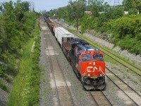A 167-car CN 310 has CN 3108 up front (with a slapdash 'CN 100' logo addded on the long hood) and CN 3089 mid-train as it passes underneath a signal gantry.
