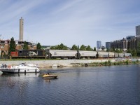 It's a holiday in Quebec (Saint-Jean-Baptiste Day) and the boaters are out in full force on the Lachine Canal as two boats pass CN 7229 and 7 grain loads, heading towards the Ardent mill (seen at far right).