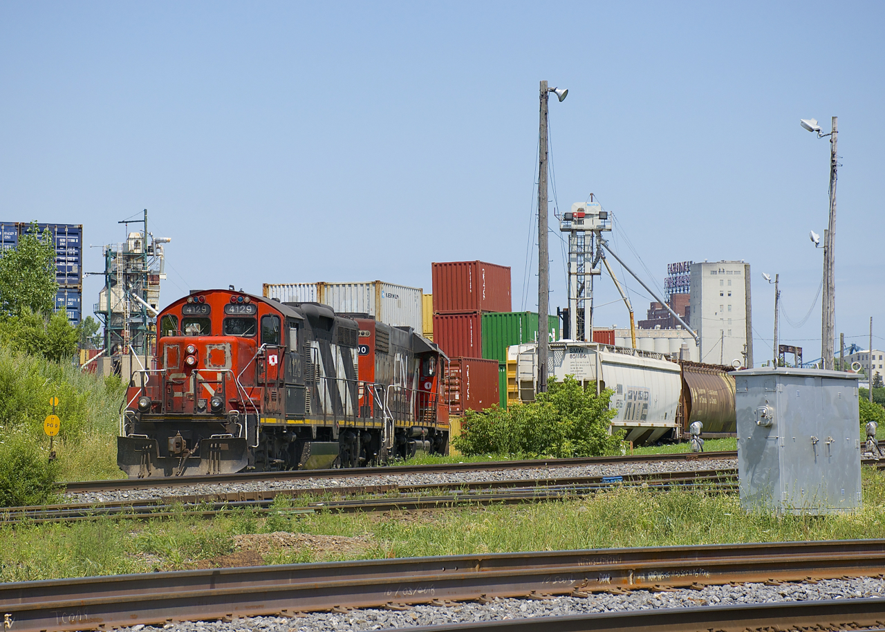 CN 4129 & CN 4700 are backing up to Ray-mont Logistics to pick up empty grain cars. This client is located adjacent to CN's Montreal Sub and Pointe St-Charles Yard and grain is transloaded here for further shipment.