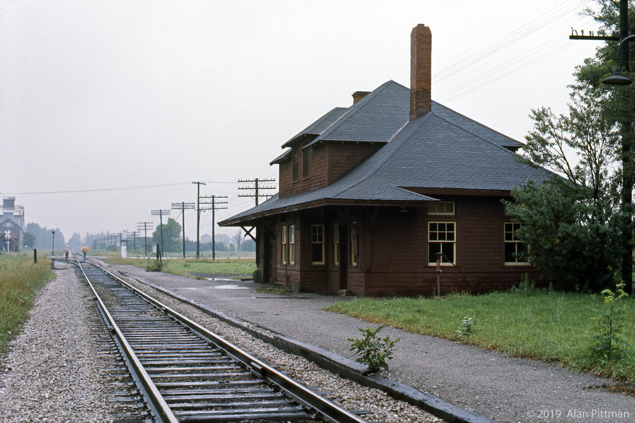 Built in the 1900's at the CP Mactier Sub crossing of Nashville Road, this CP No. 5 station design replaced an 1869 Toronto Grey & Bruce Railway structure. The station name is Kleinburg, though old Kleinburg is about 3 km away on far side of the West Humber River valley - this location is much closer to Nashville ON. Picture was taken not long before the building left this spot.
My reference says CP trains last stopped at the station in 1964, from then until 1976 the station was a (rented?) residence. By 1976 CP wanted Kleinburg station gone - I recall hearing that CP agreed to sell it for a nominal amount, on the condition that it be removed from CP property.
The station was purchased, and the structure was transported (as intact as was practical) to a new location at the north-west corner of the Kleinburg Public School grounds. Because of wires across the route, the roof and upper parts had to be removed. After its arrival, a foundation was made for the structure and the station was nicely restored, including station name signs, a baggage cart, and a semaphore signal. The brick chimneys did not survive, looks like gas heating now.