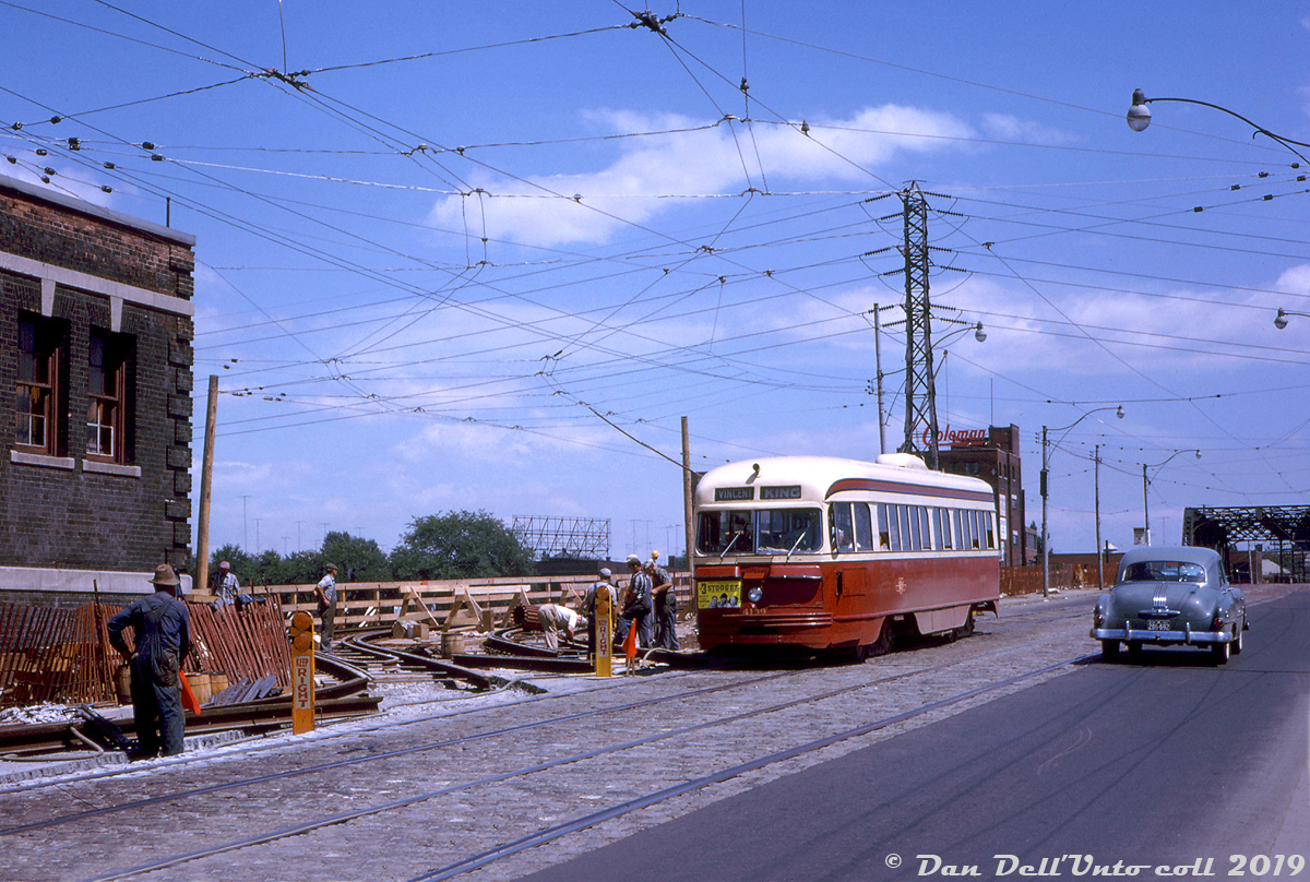 TTC PCC 4139 (the last of the TTC's first PCC streetcar order: 140 A1-class cars numbered 4000-4139 built in 1938 by CC&F) crosses the Don River bridge on Queen Street, operating on the King route bound for Vincent Loop (Dundas & Bloor). It's seen passing construction workers busy putting the finishing touches on the shoefly diversion tracks for the temporary Don River trestle where streetcars would be diverted later that day.   At this time, reconstruction work was required on the bridge carrying Queen Street over the Don River, so a parallel trestle was constructed next to it to carry streetcar traffic on the busy King, Queen, and Kingston Rd. routes while the regular bridge was closed to traffic. The overhead catenary for the diversion is already connected, and other photos from that day suggest crews were getting ready to cut in the diversion tracks into the main tracks, as streetcars were using the trestle later on that day. Streetcars operated over the temporary Don trestle from mid-August to at least the end of October while work on the main bridge was underway.  Other notable things in this photo are the Three Stooges ad on the front of 4139 (probably showing at some local theatre or venue in town), and the Coleman Lamp and Stove Company Limited building in the background, on the east side of the Don River.  John F. Bromley photo, Dan Dell'Unto collection.