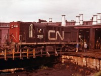 CN 3101 gets some attention from maintenance staff at the Fairview roundhouse in Halifax. <br><br>
The gentleman with a blue jacket is likely inspecting or working on some part of the truck - as there are better places for pushing an RS-18, and you'd need a lot more people.<br>
Fairview roundhouse was demolished in 1991.
