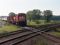 An unusually heavily powered CP TripleCrown Roadrailer train with an ex-C424 control cab CP 1100 leading 4 locomotives (looks like GP38-2, unident, Helm GP40, GP38ac) is about to cross a double-track mainline. <br><br>
I am reasonably confident that the diamond is "Melrose" where CP's Windsor Sub crosses the CN Strathroy Sub, west of Komoka ON. Anyone who recognizes the spot circa 1995 is invited to comment. <br>
Maps show the tracks at Melrose cross at about a 20 degree angle, though it looks wider - comparing ties on both lines better shows the crossing angle. I believe the CP train is en route between Windsor and London, heading east-north-east at this point. The road crossing at far right was a puzzle; I reckon it is Melrose Drive - which  appears to have been re-aligned, it no longer crosses the tracks.