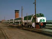 GMD F40PH GOT 511 with its train of 7 multilevel 2000-series coaches and a single-level cab car sit out the weekend beside GO Transit's fueling facilities, in this east-facing view. The reddish brown objects stacked in front of the closest pole could be brake shoes.<br>Left over from the former CN Mimico Yard here on the north side are some buildings, with the east yard tower prominent. We signed our releases and borrowed hard hats in another. <br><br>GO's F40ph locomotives were new in 1978, and GOT 511 is very clean and glossy. A CN person invited us into the cowl body engine room of an idling F40ph; he opened up a valve cover to show the exhaust valve rockers working and revved up the engine, a very loud and memorable experience. <br><br> The main line tracks of CN's Oakville sub are on the white gravel at right. The red brick buildings beyond the end of the train are close to Mimico GO station. Don't expect to be permitted into any rail yard nowadays - however Islington Ave bridge provides good views of the GO and VIA yards.