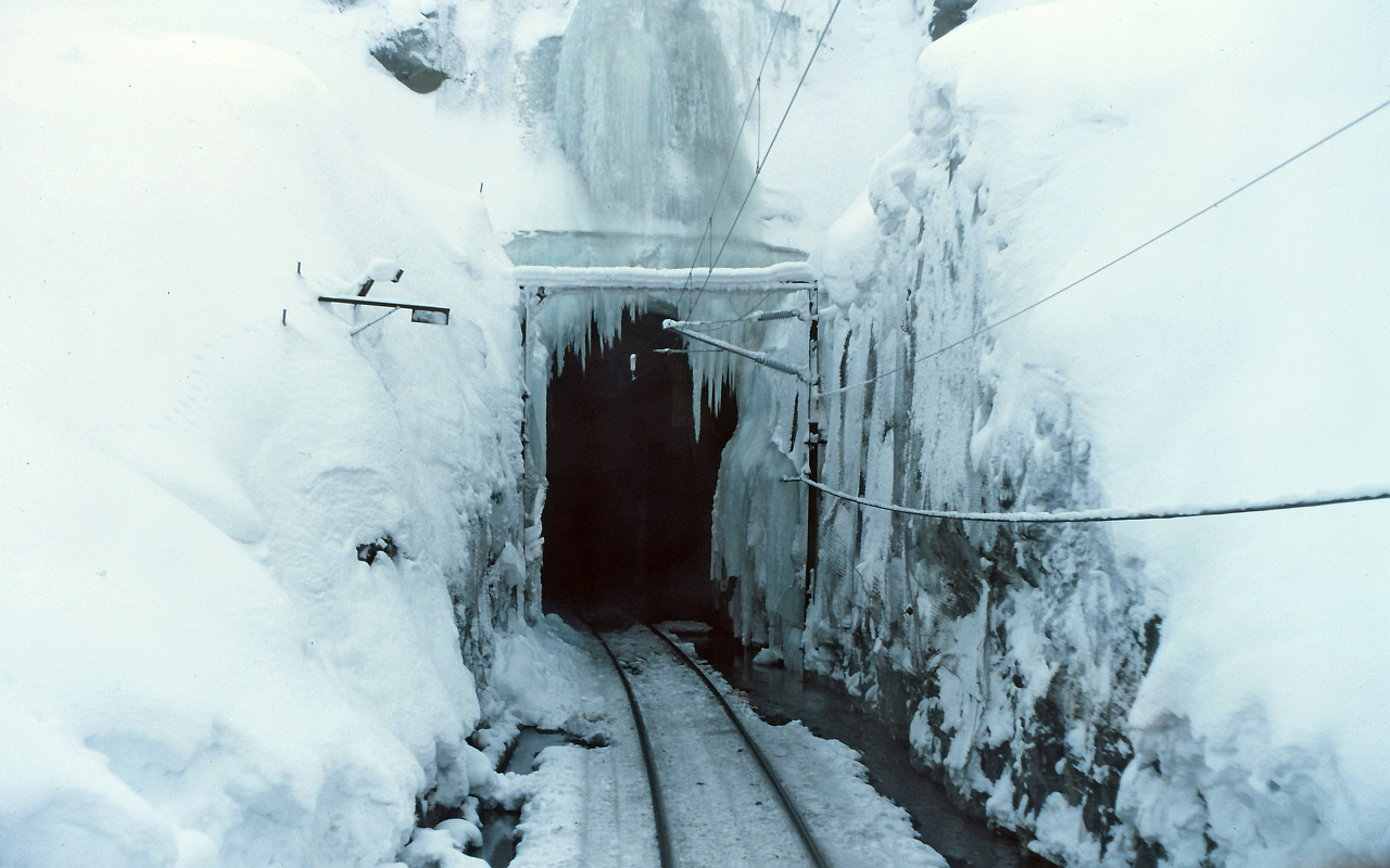 A view from the cab, looking at the north portal of the Wolverine Tunnel at mile 47.3 on the BC Rail, Tumbler subdivision. This tunnel is a non-ventilated 3.7 miles long. A typical mid-winter scene.