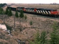 By the time we reached this location, the sunshine was all gone. 
Here, the train has come through the Battle River valley (just past where the train disappears), and is about to crest the hill. CN uses the former Canadian Northern routing through this area to get down to Ferlow Junction (probably not a junction at the time) in the valley. They stayed in the valley and proceeded SE. Grand Truck Pacific also came through here, but rather than crawling in and out of the valley, they constructed a huge wooden trestle across the depression.That trestle would end about where the last of the train can be seen. With the formation of CNR, the GTP trestle was abandoned, and the line was built to connect the tracks seen here to Ferlow Junction in the valley.