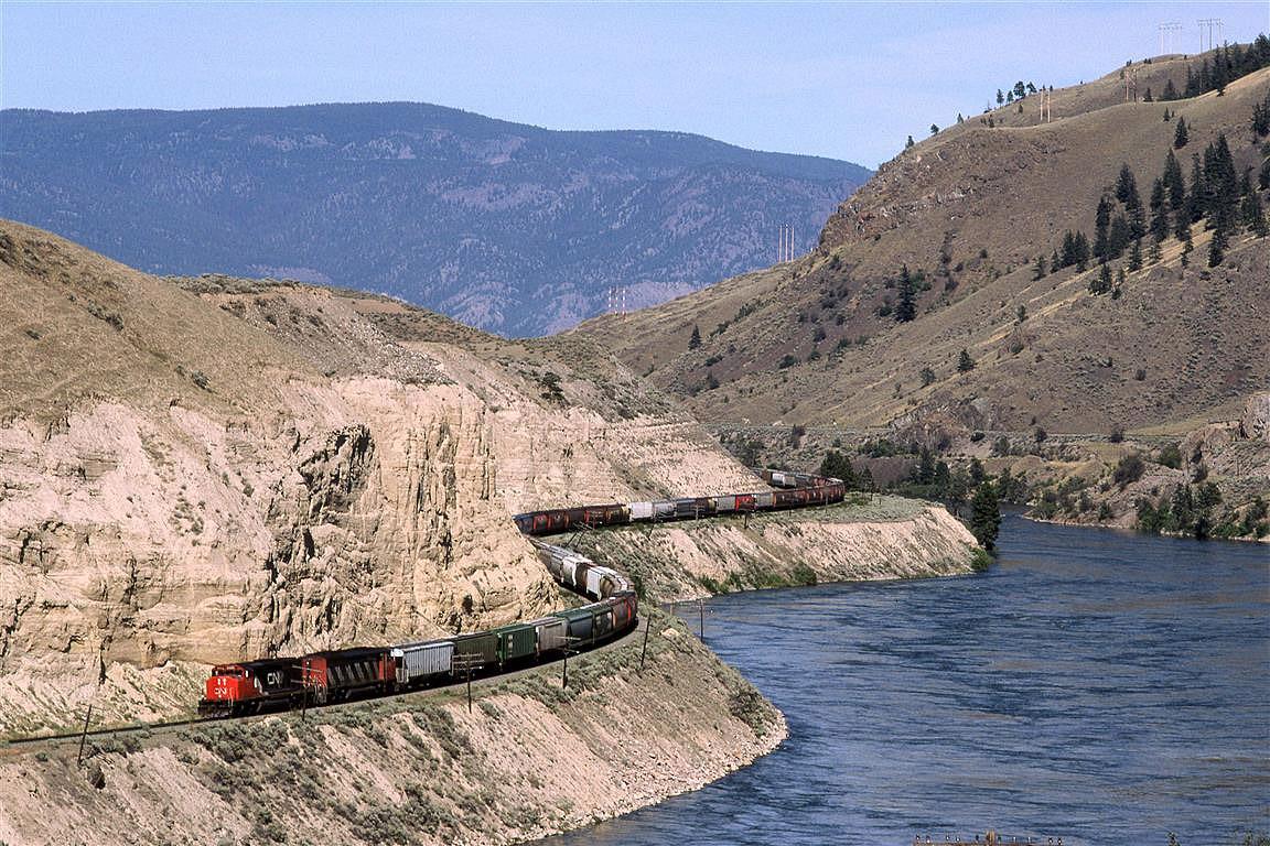 A little closer to Savona than Walhachin, This westbound CN manifest train rides a bench along the Thompson River.