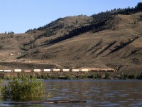 From the town of Savona, looking across Kamloops Lake, this eastbound double stack train quietly glides by on the flat, but twisted track along the north side of the lake.