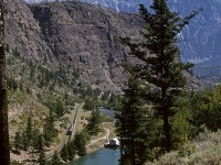 The RDC set has just left the shores of Seton Lake and is now in the narrow valley that leads to Lillooet. That water channel splits just past that little hut. The "natural flow" can be seen, but the larger channel that leads to a turbine is blocked by the trees. Lillooet is just beyond that knob ahead of the train.