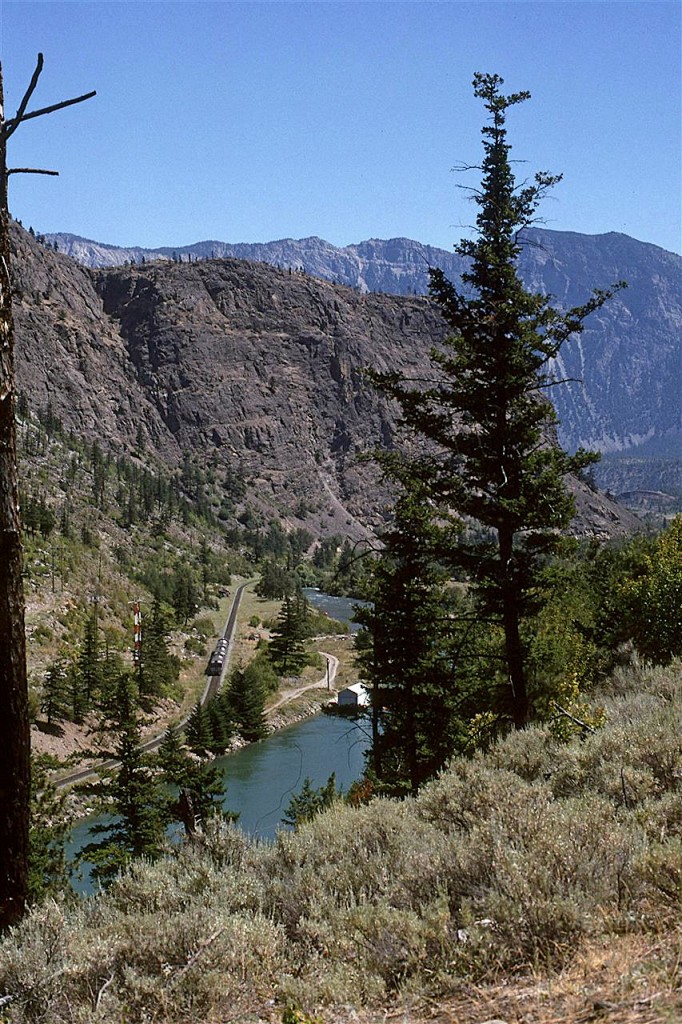 The RDC set has just left the shores of Seton Lake and is now in the narrow valley that leads to Lillooet. That water channel splits just past that little hut. The "natural flow" can be seen, but the larger channel that leads to a turbine is blocked by the trees. Lillooet is just beyond that knob ahead of the train.