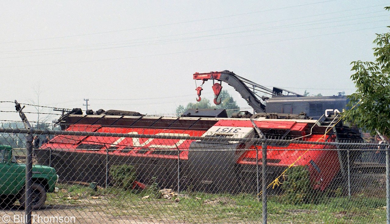 CN RS18 3151, one of the six RS18 units CN rebuilt for the new Tempo train corridor service that started just a few months before in June 1968, sits on its side after derailing on Sarnia to Toronto Tempo train #150 one mile east of Oakville. CN crane 50109 in the background is on the wreck train, working cleanup duty at the site.

For an overview photo of the derailment, see: http://www.railpictures.ca/?attachment_id=38626