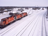Its that time of year again, where winter photos look comfortable compared to the summer heat.  

It's a busy morning in Brandon as two sets of GP38's are seen switching the west end of the yard. In the distance a westbound grain train pulls down the main towards the station for a crew change. 