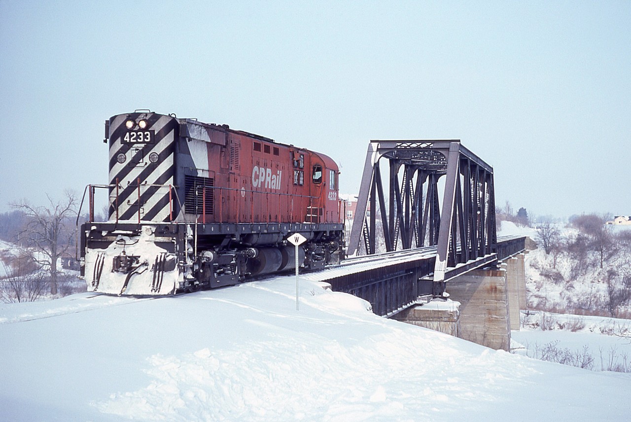 Quite a while back I posted a couple of photos of an "Outing of the Privileged"; a CP special running from Brantford down to Waterford in order to 'inspect' the new CP/CASO connection there. In July 1983 CP purchased land for a right-of-way to connect from TH&B Waterford Sub mile 78.9 over to former LE&N Simcoe Sub mile 35.3, resulting in a gentler grade and more efficient access to the old CASO, enabling the Hamilton-Nanticoke steel train a smoother run. The old LE&N bridge over the CASO was redecked. The inspection train came down (image #35147 in RP)the old west wye and then backed eastward out my vision to the station around the bend, then the CP4233 ran up and over the bridge light power. As seen here, the first power to run over the new decking. I never did see or hear of the Select Few that were in the cab. It was a bitterly cold day and I was actually expecting the whole train of 4233, a Budd, two coaches and a caboose to make the crossing. But no. The unit, lite, reconnected with its train and off they went. I was far too frozen to hang around to see what else transpired. I assume they just returned to Brantford via the new route.
Perhaps someone in the know can shed a bit of light on this adventure.