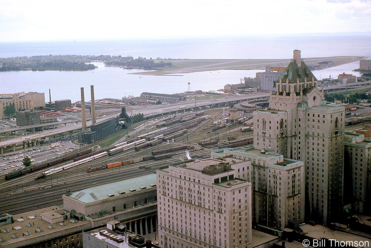 Here's an aerial view of the downtown Toronto railway lands taken from the Bank of Commerce building's observation deck in September 1964. Visible in the foreground is Toronto's Union Station on Front Street, opposite the CPR's famed Royal York Hotel.

Behind the station's train sheds are CPR's John Street coachyards, roundhouse and servicing facilities for both locomotives and passenger cars (CN's Spadina facilities are out of frame to the right). A switcher is visible moving around stainless steel Budd equipment for The Canadian, amid plenty of heavyweight and lightweight steel coaches in the yard. A pair of F-units can be seen on the servicing tracks near the roundhouse by the old coal tower, along with a pair of Budd RDC cars ("Dayliners" in CP parlance).

Nearby is the Toronto Terminals Railway Central Heating Plant (which supplied steam heating to downtown buildings including Union Station, the Royal York, and CP's John Street facilities). Along the harbourfront are buildings for Yardley's (perfumes), the Terminal Warehouse, grain elevators, and various piers. The Toronto Island airport is off in the upper right.