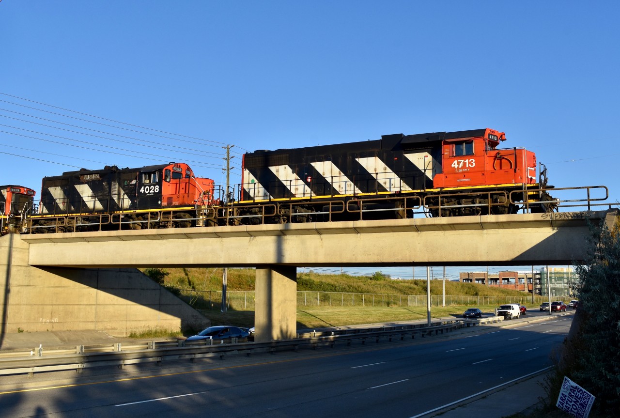 After having just finished spotting a long stash of empty autoracks into Chrysler, CN 579 is seen slowly creeping over the Airport road overpass at the end of the North Park Spur as they prepare to run light back through BIT in order to re-couple on to the loaded autoracks which they pulled a couple hours earlier. Timing is 07:24. Generally this local will be nocturnal for the most part as crew is scheduled to go on duty at 23:30 in MacMillan Yard but every so often comes the odd morning when they are still operating under first rays of light (especially this time of year) and I guess I just happened to pick the lucky morning today! Power is CN gp40-2 4713, gp9rm 4028 and out of sight, GMD-1U 1439 + gp9rm 4130.