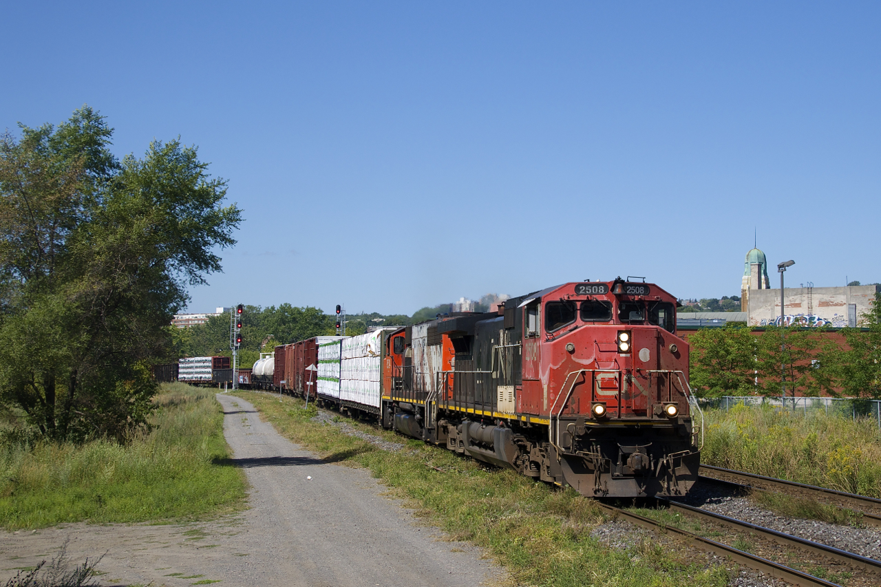 Faded units CN 2508 & CN 9524 lead a 57-car train CN 324 around a curve in the St-Henri neighbourhood of Montreal.