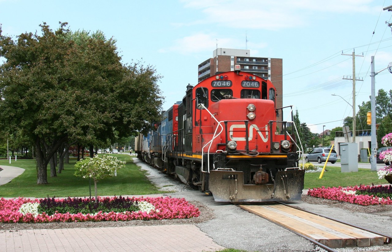 CN GP9Rm 7046 shoves through Sarnia's waterfront Centennial Park with a pair of GTW units and two hoppers for the Cargill facility at the Sarnia harbour.