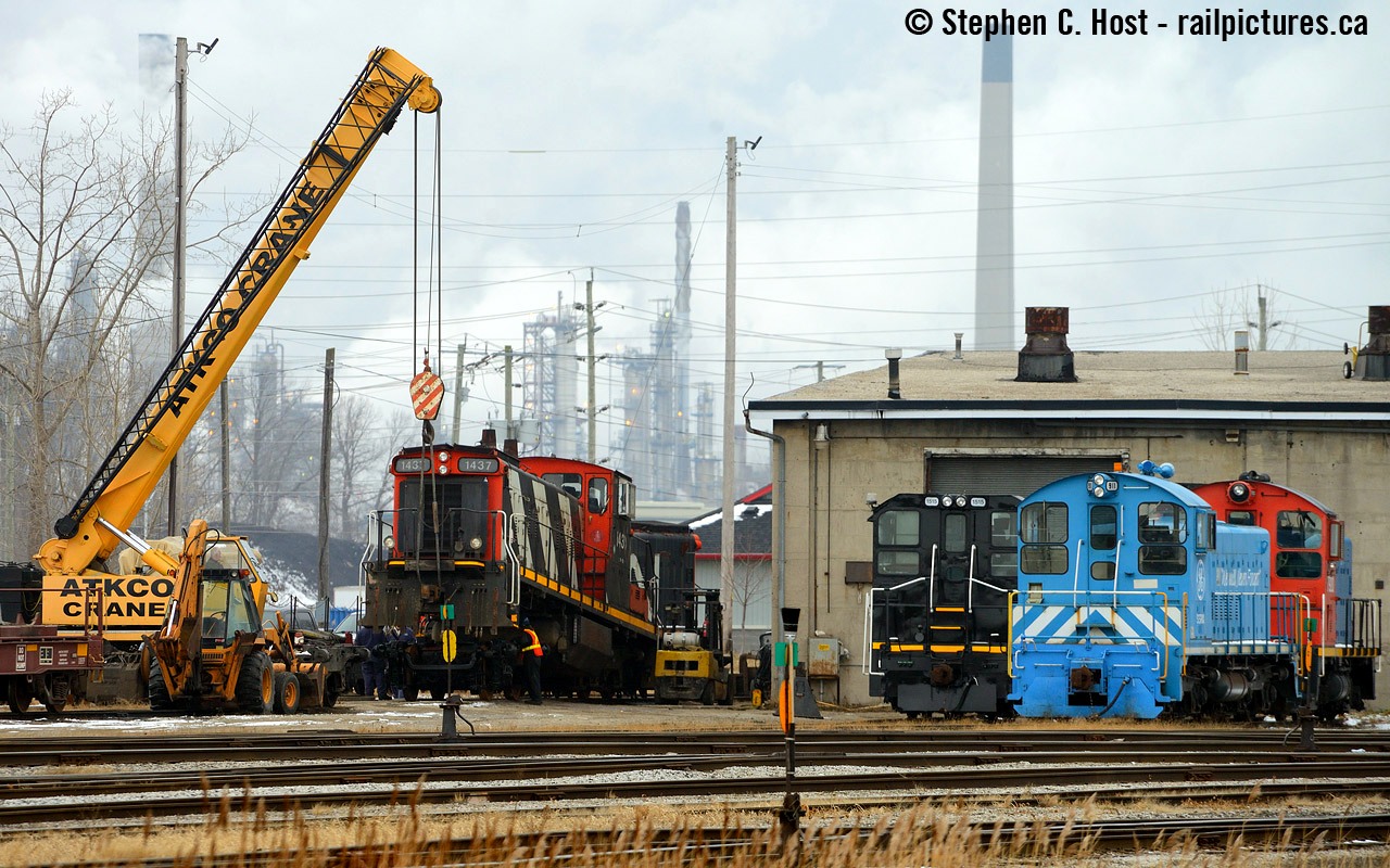 Action at the CN Sarnia Roundhouse on New Years Eve as CN  1437 gets a new combo/wheelset provided by the capable men of Lambton Diesel Services. To the right is the usual motly crew of Switchers owned(?) by LDS including: Esso (ex CN) 7920, General Electric (SSRX) 911, and the black one is 1515 with LDS lettering on the sides. The Esso unit has been here off and on over the years, usually for repairs, but now "6900" former EMD switcher is at the Esso plant and this one has been at LDS ever since (a few years now).
