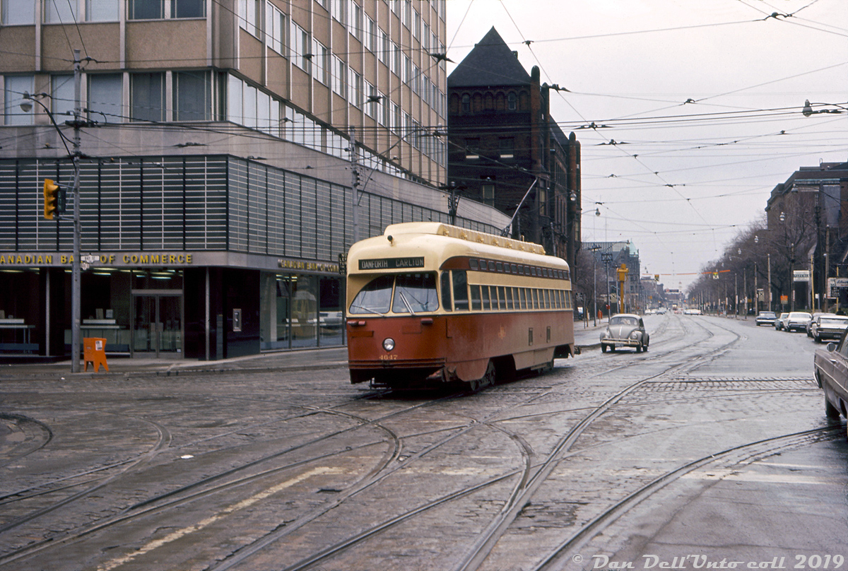 Taken from one of the centre streetcar loading platforms, TTC PCC 4647 (an ex-Cleveland A11-class car) operates on the Carlton route, heading eastbound through the intersection of College Street and Bay Street on a rainy Friday. One of the ever-present Volkswagen Beetles follows close behind (looking a little maimed from a fender-bender). Hiding behind the office building with the CIBC (whose branch is still there today!) is the old "Victoria Hospital for Sick Children" building at College & Elizabeth, built in 1891 (also still present today).

TTC 4647 was one of the A11-class of 50 PCC's built by Pullman in 1946 for the Cleveland Transit System and acquired secondhand by the TTC in 1952/53 (4647 was originally CTS 4222), and featured distinctive rooftop ventilators travelling the length of the cars. The last of this series were retired in the early 80's, and two cars survive at the Halton County Radial Museum (4631 and 4668, as work cars W-30 & W-31). 4647 had a notable ending to its career: while being towed one rainy night by a service truck from Wychwood carhouse to Hillcrest Shops for scrapping in November 1981, 4647 broke loose down the hill on Bathurst Street near Davenport and became a runaway car. It made its way on its own down Bathurst as far as King Street, where it derailed and smashing into the side of a building. Due to quick actions by police, there were no injuries or casualties.

Robert D. McMann photo, Dan Dell'Unto collection.