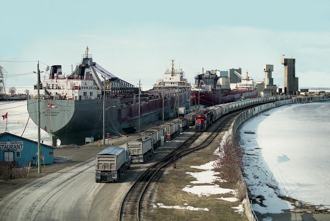 This has to be about the busiest I have ever seen it up by Goderich's Sifto Salt Mine. Sure, there is a couple of lake ships tied up for the winter, and RLK 4096 & HLCX 6522 are working a long string of salt loads; but look at the trucks!! They are lined all the way up to the entrance, as the start of the line can be seen up behind the train. There must be 40 of them. Perhaps someone on this group can explain why so many, and how long would it take for them to get their loads and get out of there. Seems like a long wait.
I was wondering if they line up, first come first serve, and loading does not begin until a certain time. But I would expect a place like this to be a 24 hour operation..............