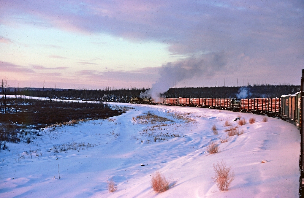 From December 1973 or January 1974. My view from the caboose near mile 809 or at Nig Creek on the BC Rail Fort St. John sub. We had departed our crew change point at Beatton, mile 816.5 and heading south to our home terminal at Chetwynd mile 659.3. Looking at the images it was a bitterly cold morning. Thank goodness for the two oil heaters in the caboose. The images show a typical train of that era, logs, boxcars and tanks. Also we could have pellet sulphur, wood chips and other general freight as well as TOFC. The track at the time was in reasonable shape and we would rock & roll along at 25 mph. I do not recall why the RS3 was mixed in with the loaded log cars although there are two RS18's on the head end and I don't recall any unit weight or axle restrictions on bridges etc.  When I left Chetwynd for the last time in 1976, the track was in rough shape north of Fort St. John with 90 continous miles at 10 mph, making for some incredibly mind numbing trips.
   Note the TH&B boxcar, a long way from home. Perhaps it had been previously loaded with track spikes from Stelco or farm machinery from MF in Brantford. At the time of this image I had been "out west" less than a year and the TH&B box car was a fond memory of my previous employer, the TH&B.
all ancient history and memories. 
thanks for looking.