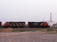 A view only available on an overcast day. Actually, it may not have been cloudy this evening. It may have been smokey.
101 was a hot train that arrived in the early evening if all went well.
Behind the train is the former Swift Premium meat packing plant, the last survivor of several such facilities in the immediate area. In fact some stockyards still existed to the left, although I never saw them used during my time in Edmonton.