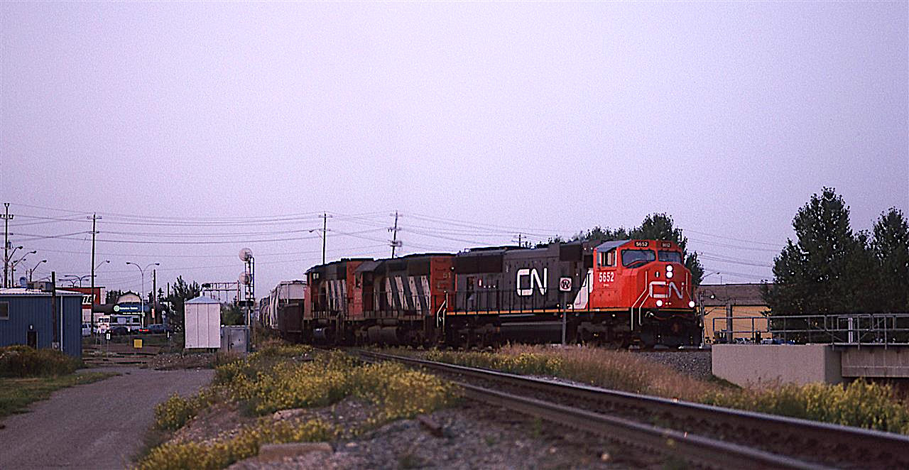 This is another fading light shot that taxed the film and scanner.
526 is coming into Edmonton, from Scotford Yard in Fort Saskatchewan and is on the east leg of the wye of the Vegreville sub as it joins the Wainwright Sub as East Junction. It brings in many chemical cars that are destined for points east, therefore, it goes to Clover Bar Yard on the east side of town. I think that from there, it might switch out some cars and then head east as a 200 train.
The beginning of the bridge at right is to cross over the LRT tracks