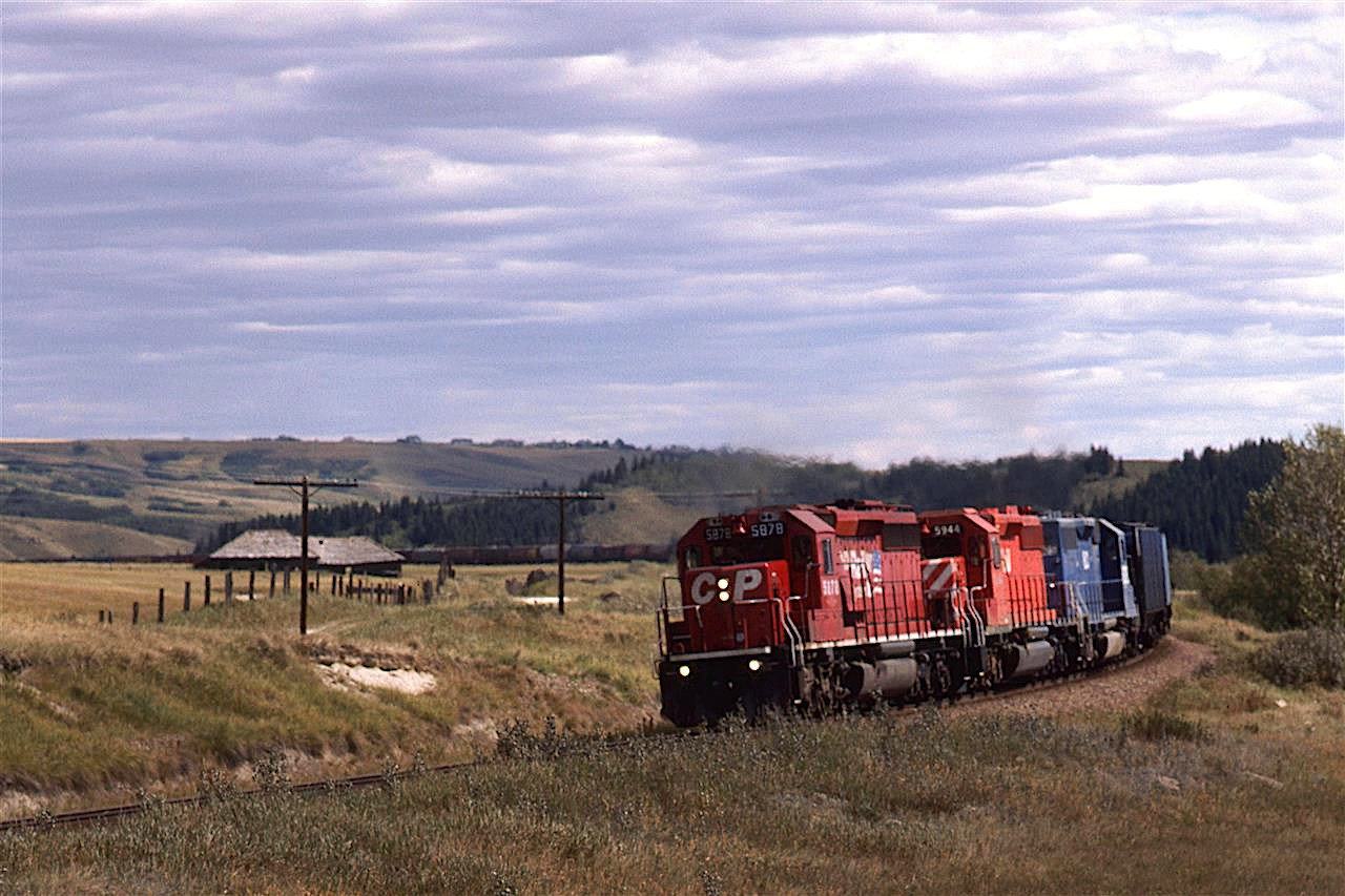This westbound grain train is passing all that remains of a once-thriving Glenbow. Apparently, that building was the store.
I don't know if this shot is repeatable, even though this is now public land. The Glenbow Ranch Provincial Park pamphlet says that one must stay on the paths. If this is strongly enforced, and the new fencing put in is too restricting, then I would have to say that they ruined it for us.