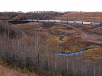 Another view of 550 as it continues down Camrose Creek Valley. The treatle that the train is occupying is no more. It is now an earthen berm. 
Those hoppers are probably going to the polyethylene plant a Joffre AB. 